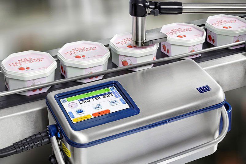 Hier wird von oben das Haltbarkeitsdatum gedruckt, während die Eisbecher nach links rollen. Quelle: Bluhm Systeme